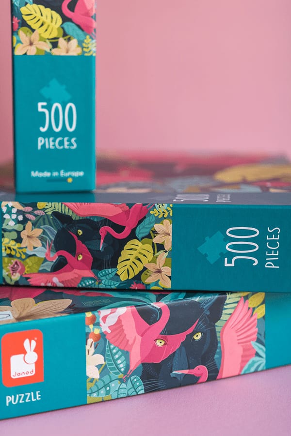 Boxes of puzzles featuring tropical animal and floral designs, indicating 500 pieces each, with one box showing a flamingo and panther among leaves and flowers.