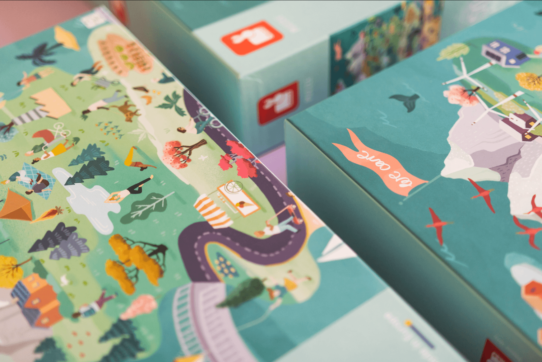 Colorful illustrated map on board game packaging showing outdoor scenes, people, trees, and pathways.