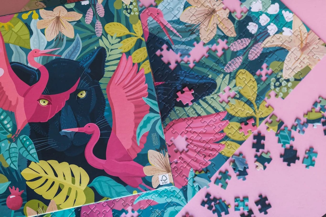 Colorful jigsaw puzzle with tropical jungle scene featuring pink flamingos, black panther, and lush green foliage, some pieces are assembled while others are scattered.