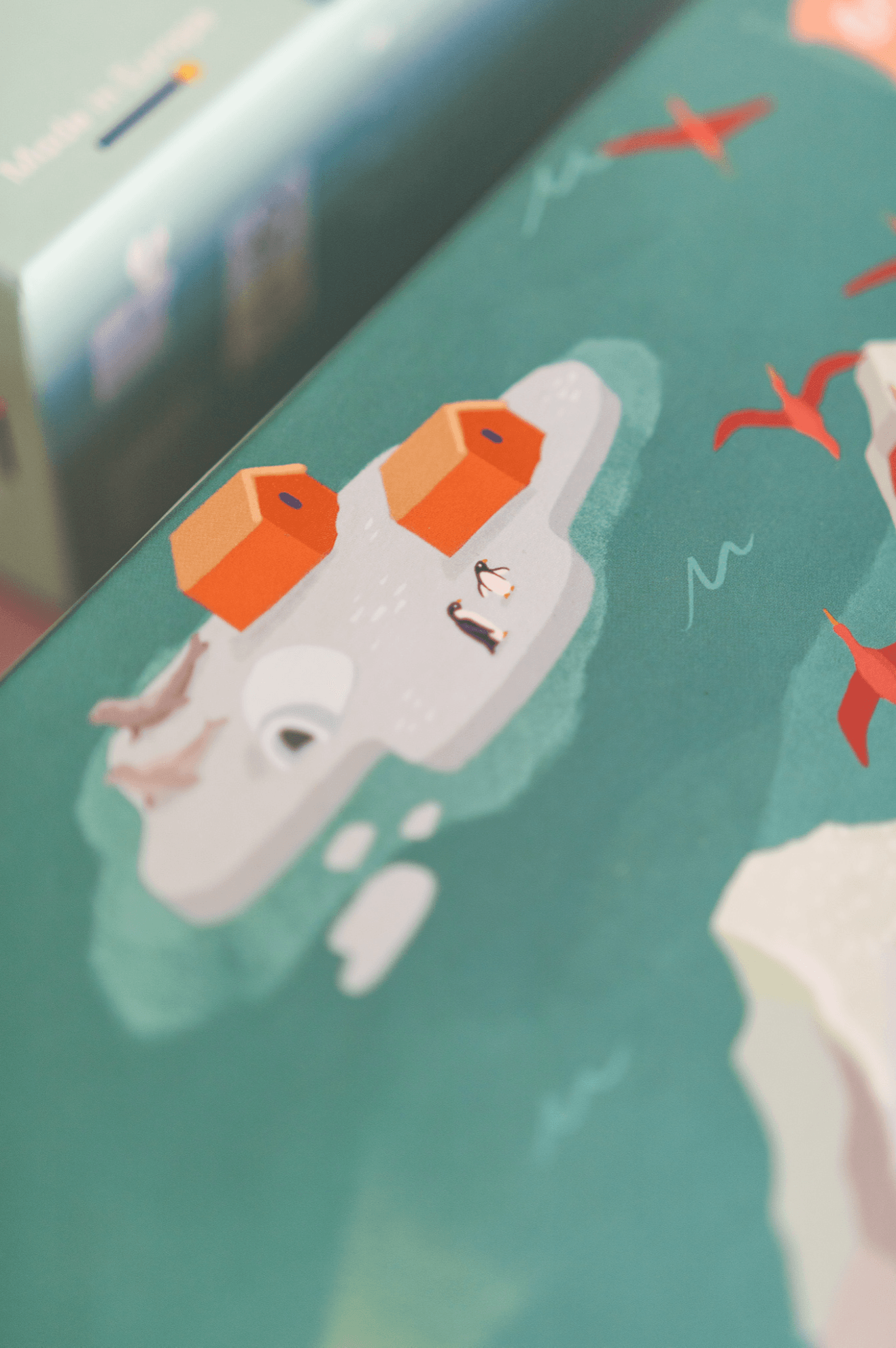 Illustration of an icy island with two orange buildings, penguins, and flying red birds.