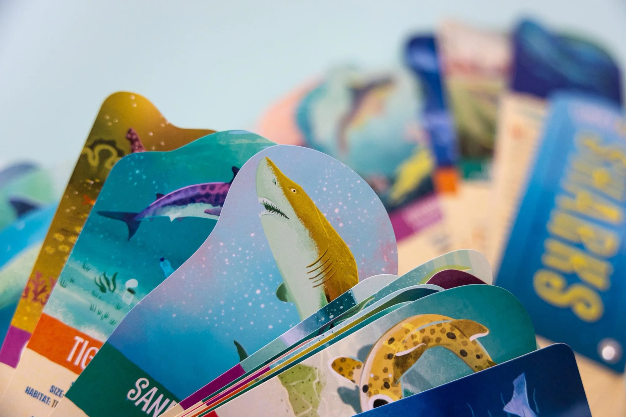 A collection of colorful illustrated animal cards fanned out, including a shark, a dinosaur, and a spotted animal, with a blurred blue box labeled 'STAMPS' in the background.