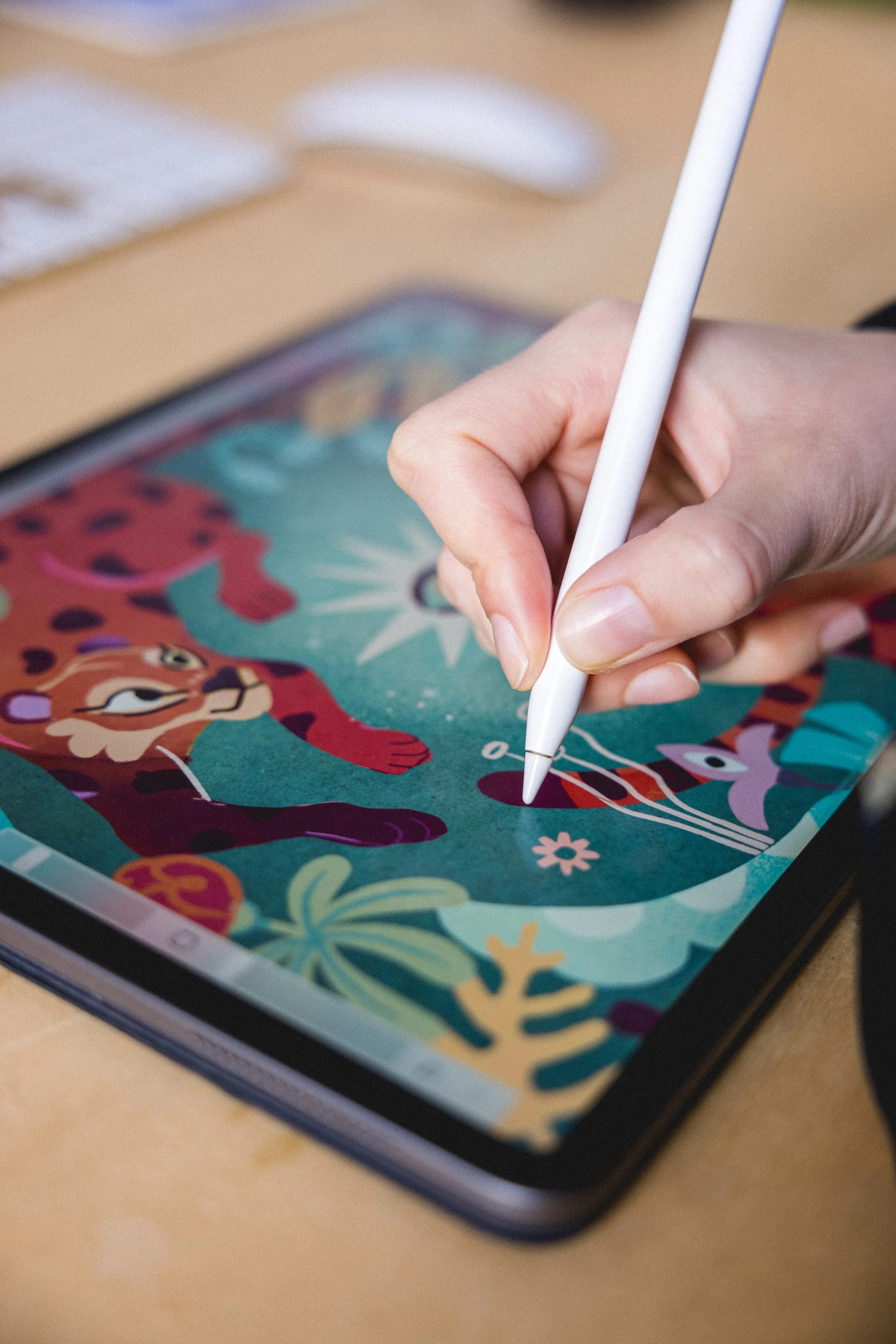 A person using a stylus on a digital drawing tablet displaying colorful cartoon characters and plants.