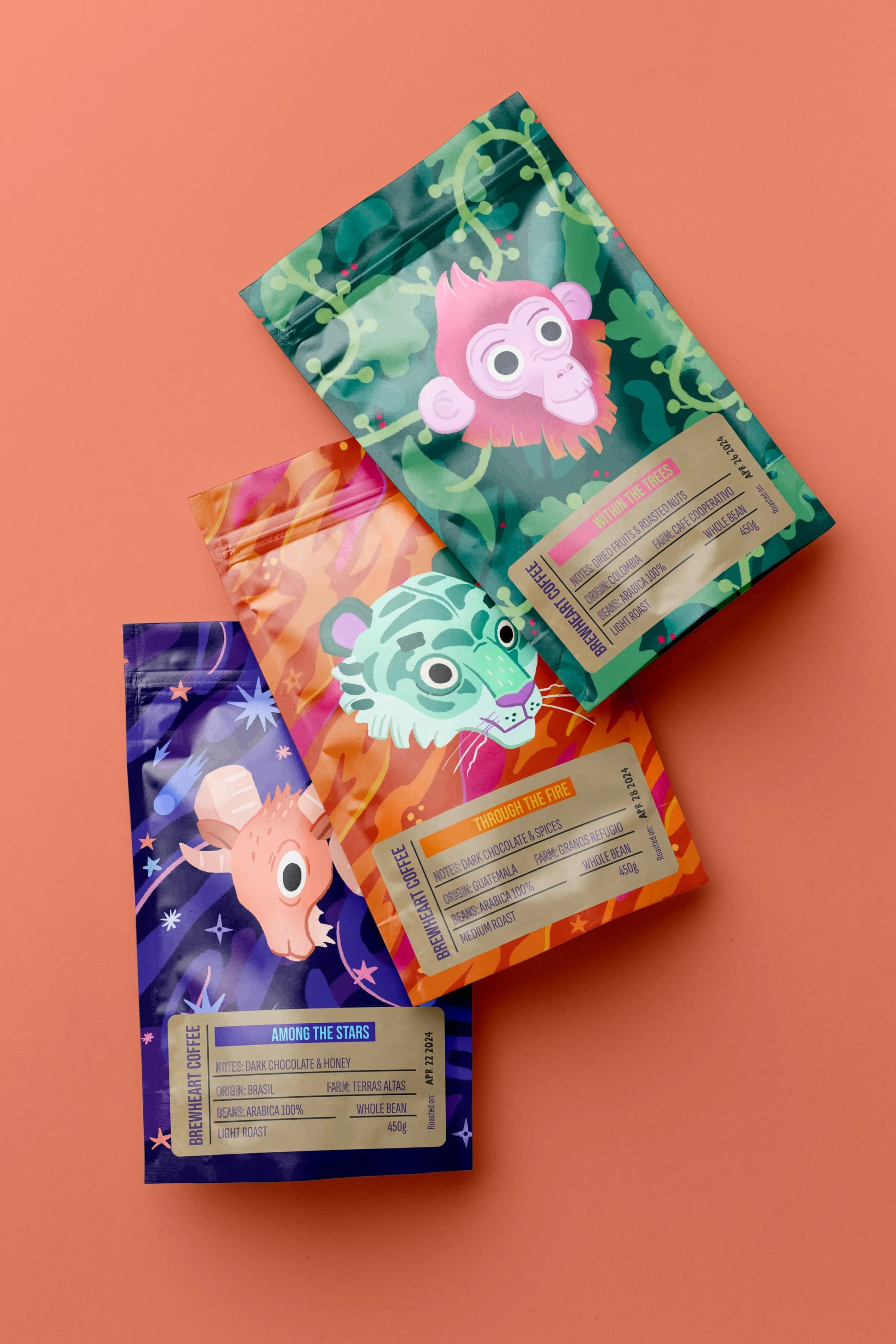 Three colorful coffee bags with cartoon animal illustrations on a peach background.