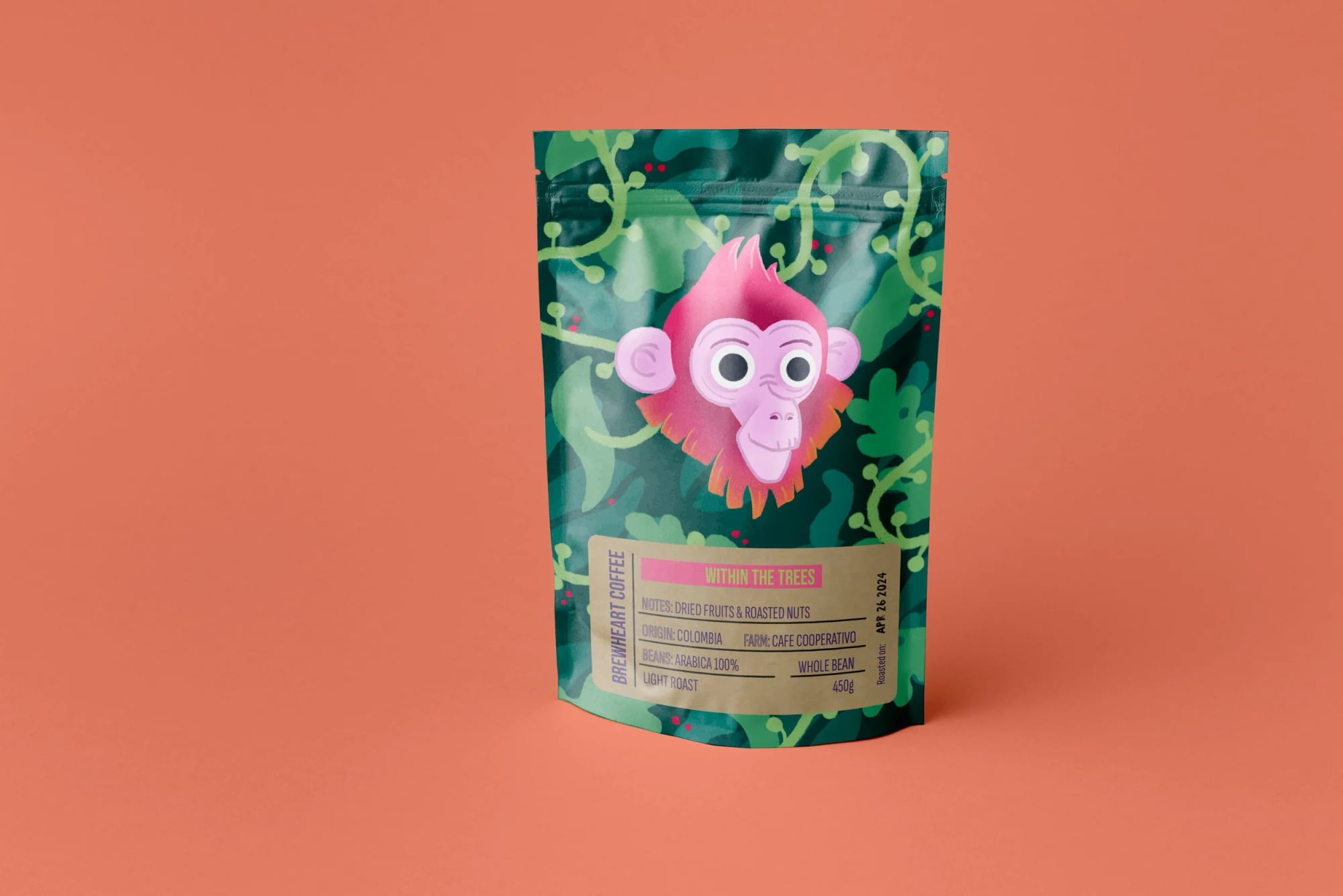 A colorful coffee bag featuring a cartoon pink monkey face with large eyes and a tuft of hair, set against a leafy jungle background. The label indicates it is coffee from Colombia with dried fruits and roasted nuts, a whole bean light roast, weighing 450 grams.