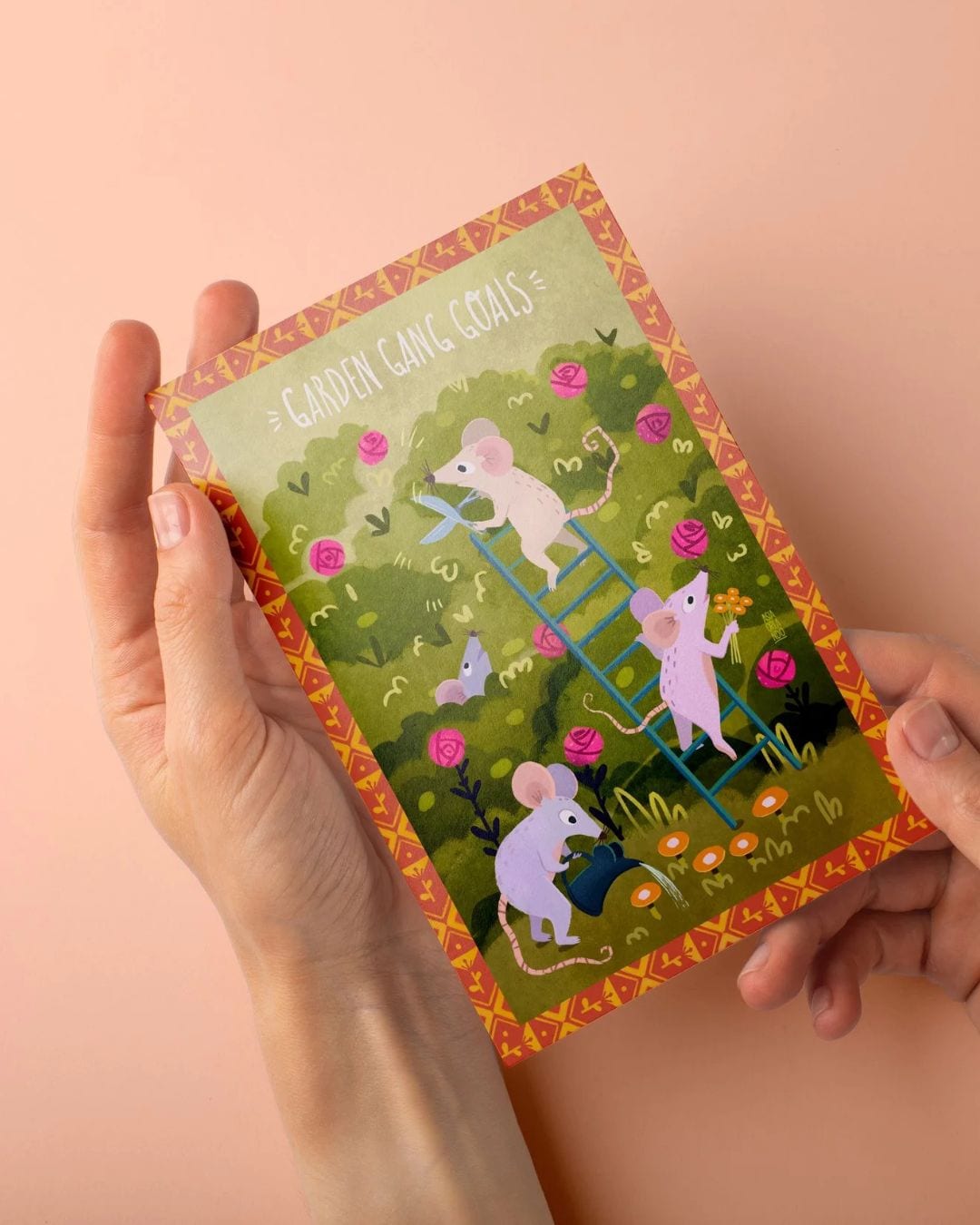 Garden Gang Goals postcard held in hands — mice tending to a rose bush.